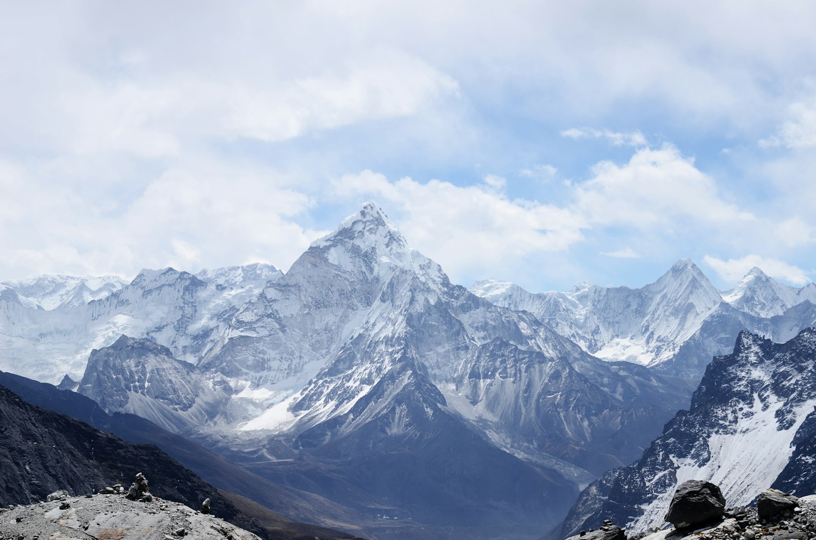 Cloud drifting across high snow-covered Himalayan peaks seen from a quiet valley ridge