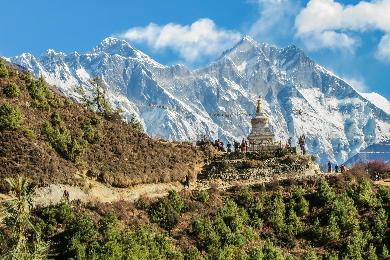 Prayer flags and a white stupa below bare mountain ridgelines, Nepal Himalaya