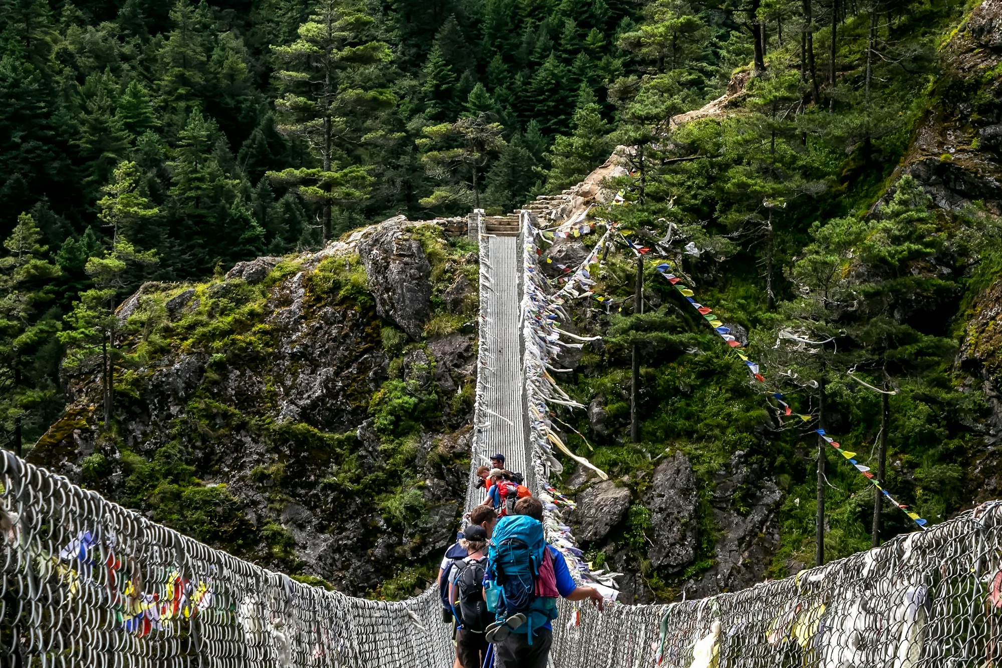 Trekkers crossing a suspension bridge on a high Himalayan trail, Nepal