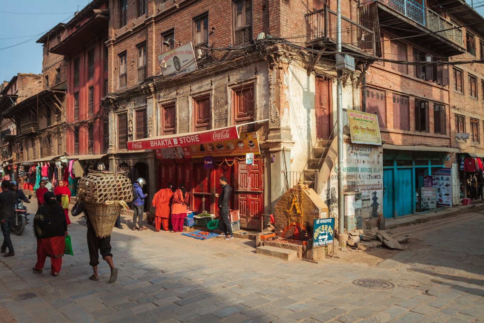 A street corner in Bhaktapur with old Newar brick houses and a porter carrying a traditional doko basket