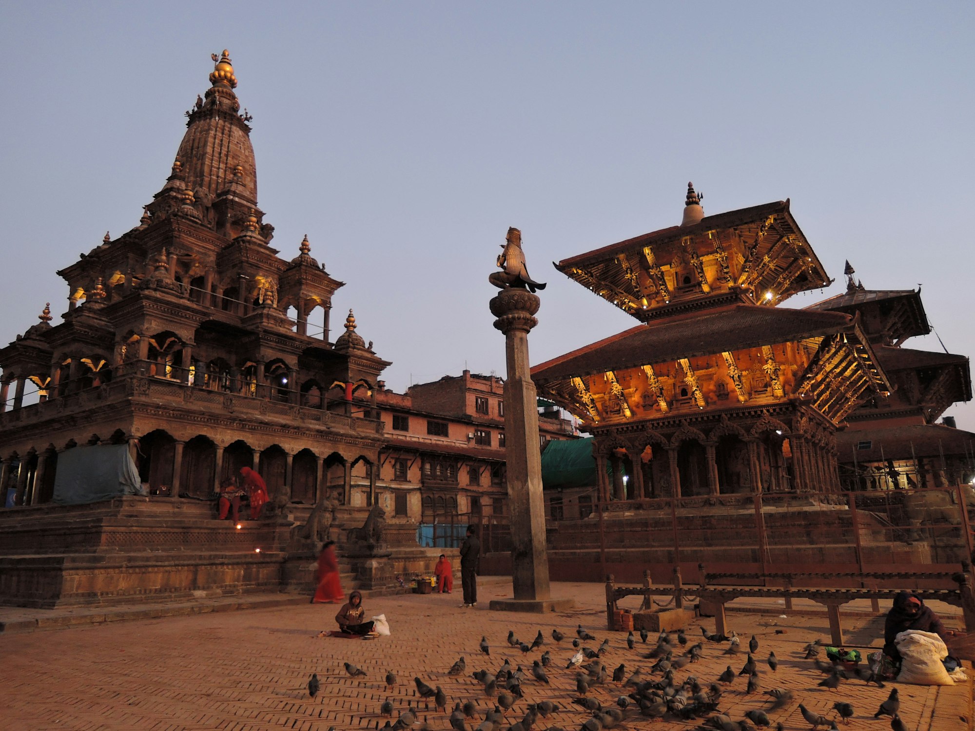 Patan Durbar Square at dusk, the stone Krishna Mandir and a gilded Newar pagoda glowing over the brick plaza