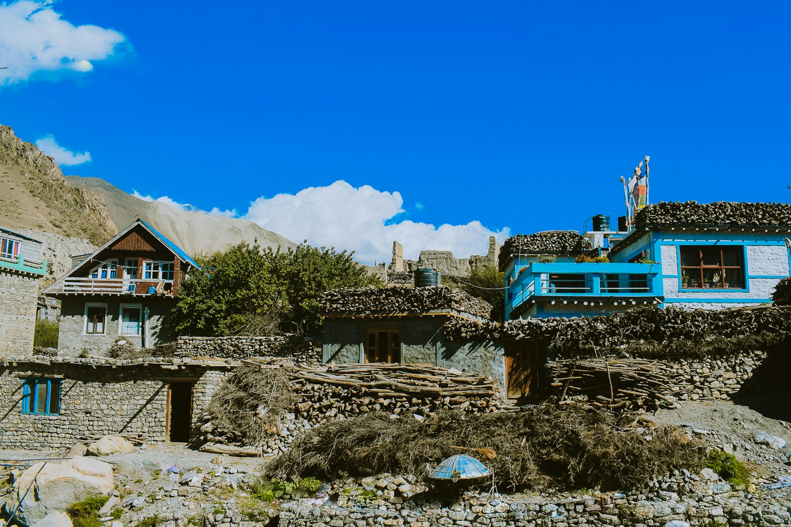 Traditional flat-roofed stone village of Lower Mustang with prayer flags below dark mountains at dusk