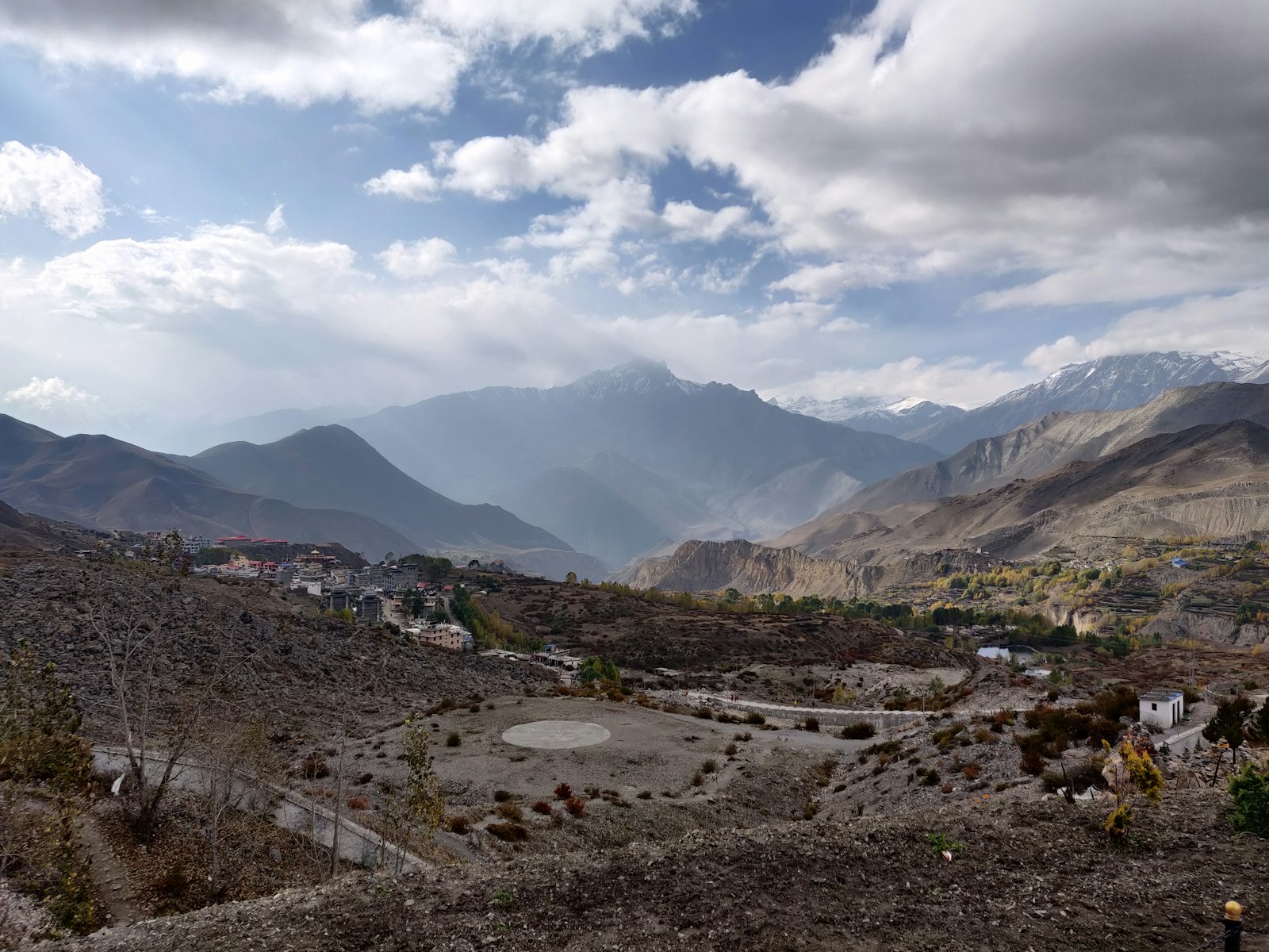 A Mustang village set in a wide valley below hazy Himalayan ranges near Muktinath, Nepal